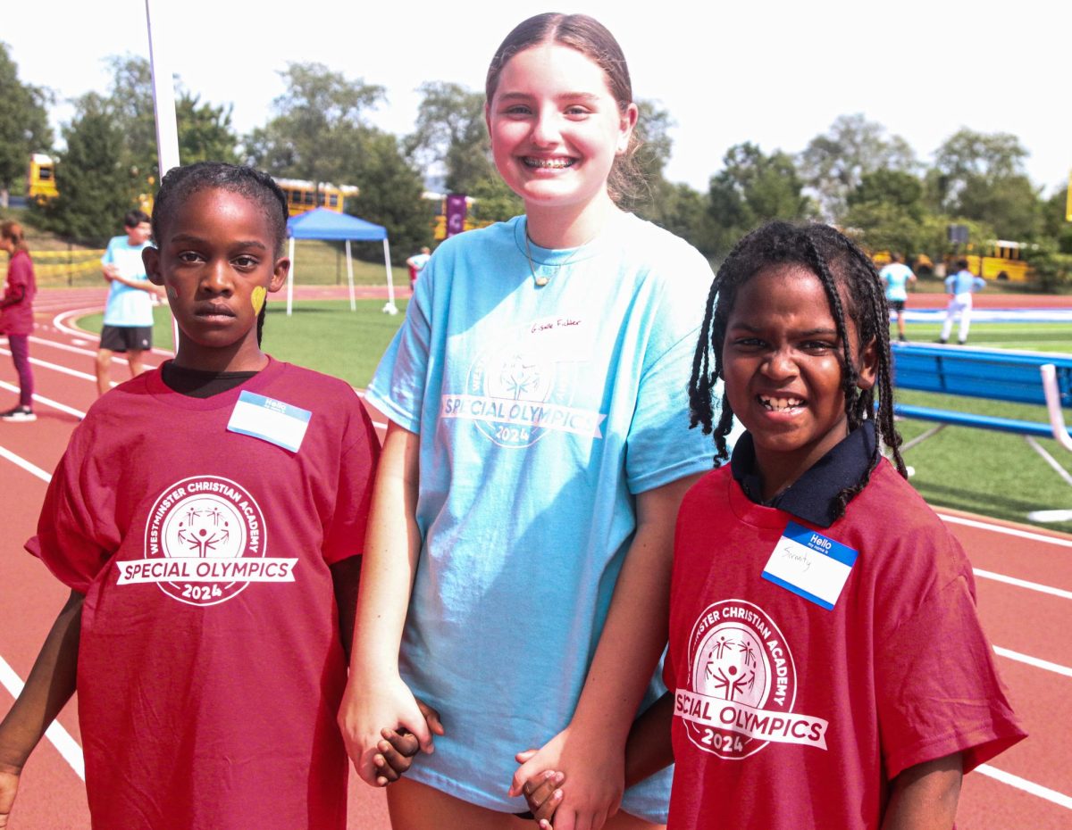  A student volunteer engages with two excited special olympics athletes