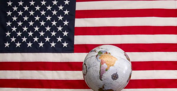 A globe being disproportionately shown against a United States flag. 