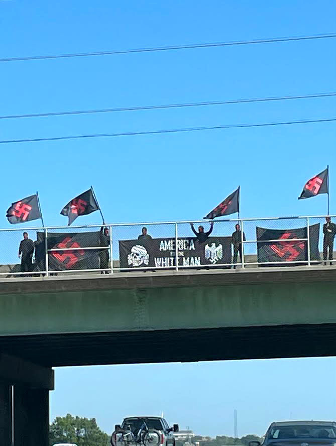 Rally goers fly swastika flags over the overpass