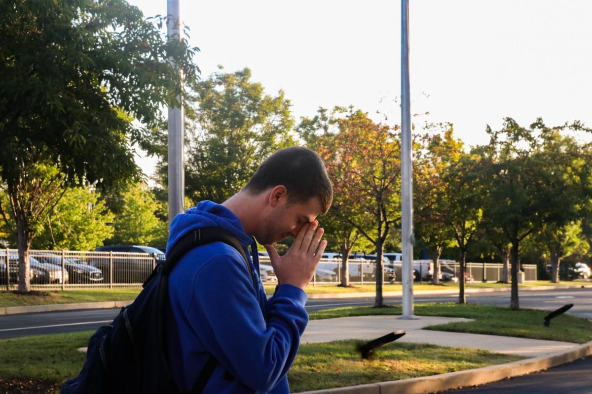 Shepherd Perkins, Senior, bows his head in prayer while smirking to himself.