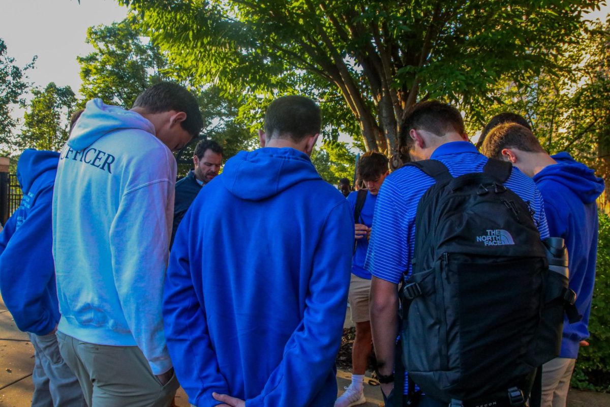 A group of all boys bow their heads in a deep prayer led by David Ottolini.