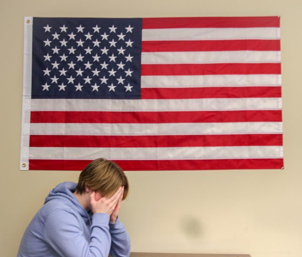 Student mourns the loss of Jimmy Carter in front of the American Flag